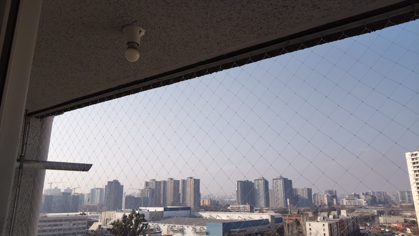 Malla de seguridad instalada en balcón con vista a Santiago